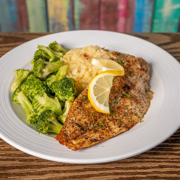 Seasoned fish fillet with lemon, rice pilaf, and steamed broccoli on a white plate.